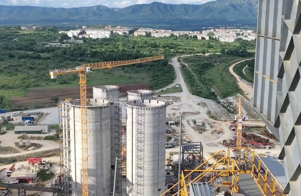 Vista aérea de dos silos de almacenamiento en concreto con grúas torre en operación, sobre el conjunto de la planta.